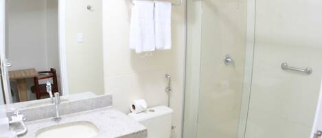 Un baño con lavamanos, inodoro y ducha de vidrio.