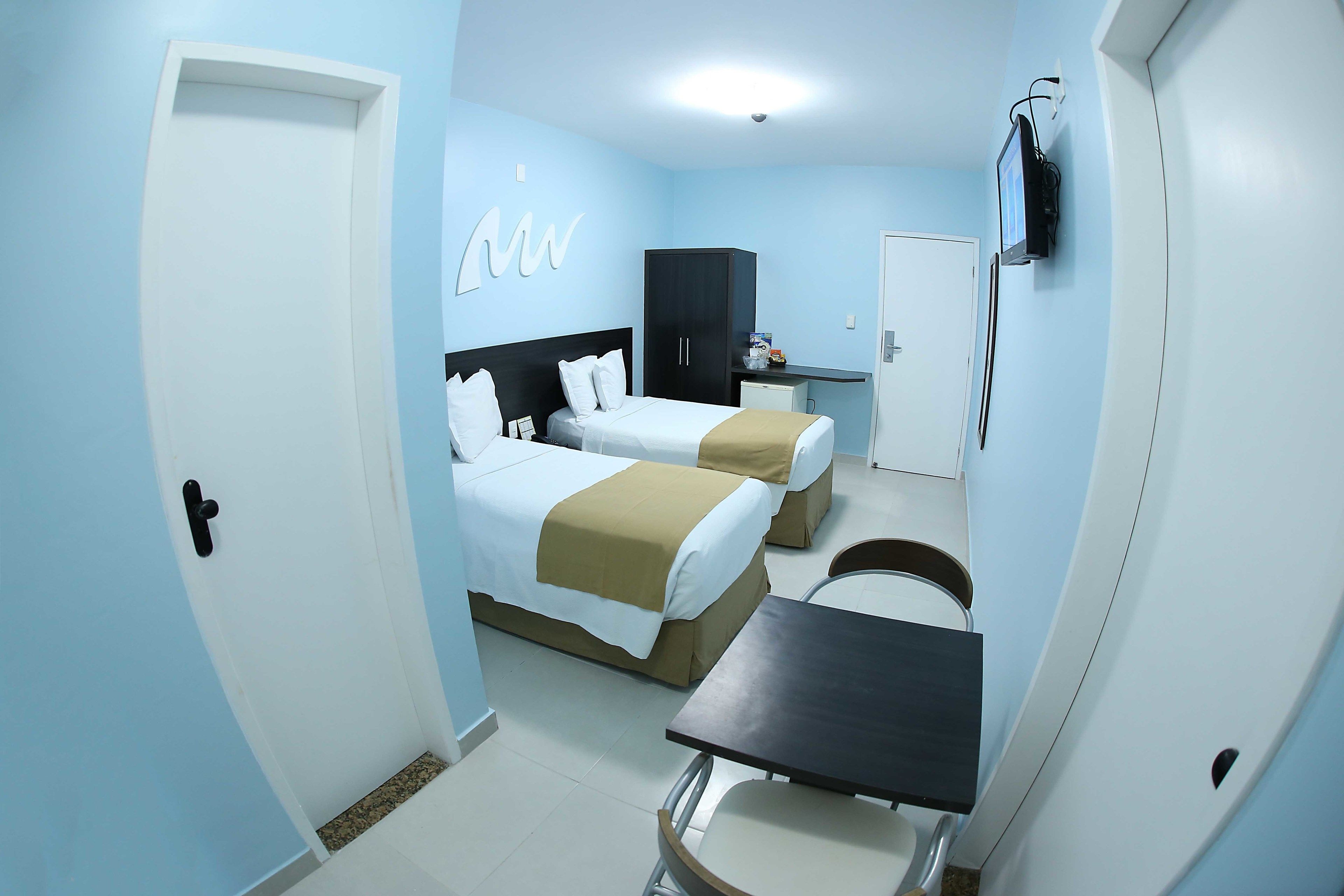 Une chambre d’hôtel avec deux lits, un bureau, une chaise, une télévision et une armoire.