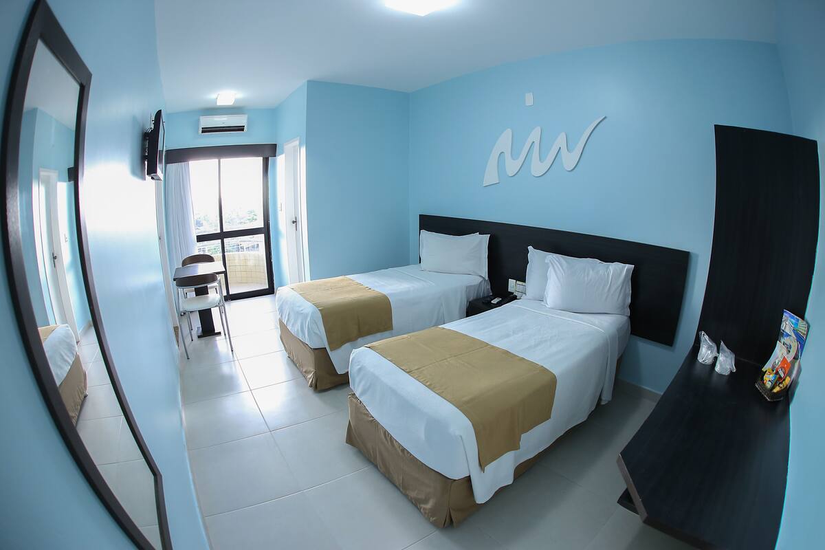 A hotel room with two beds, a desk, and a chair.