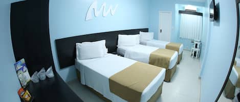 A hotel room with three beds, a desk, and a TV.