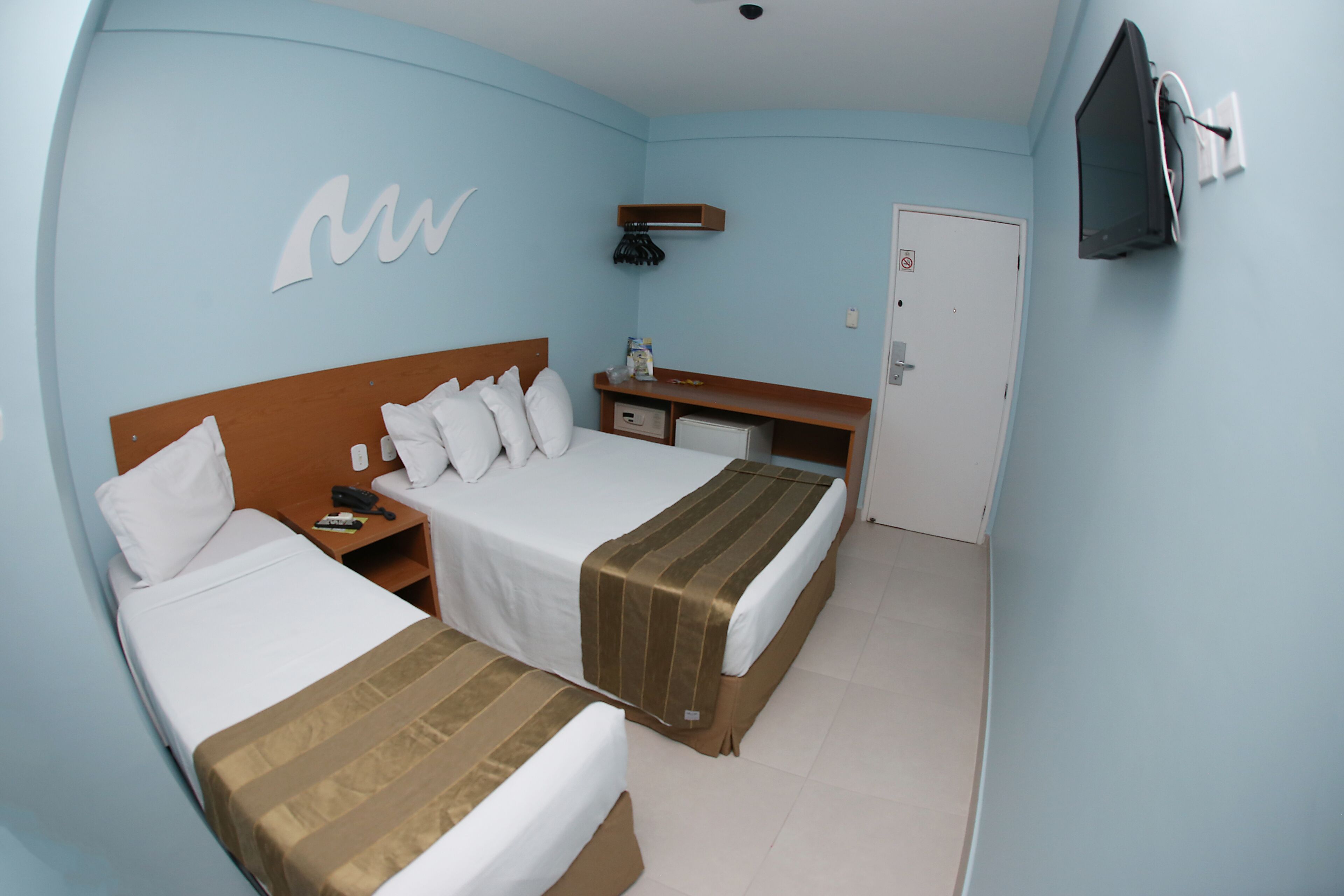 Una habitación de hotel con dos camas, un escritorio, un televisor y una puerta.