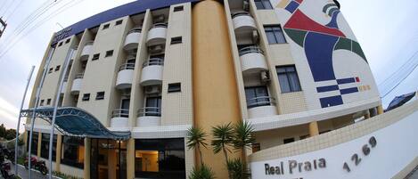 Un hotel con fachada curva, varios balcones y un cartel llamativo que dice "Real Praia HOTEL".