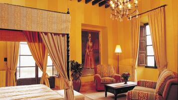 A room with a four-poster bed, a chandelier, a sofa, and a painting on the wall.