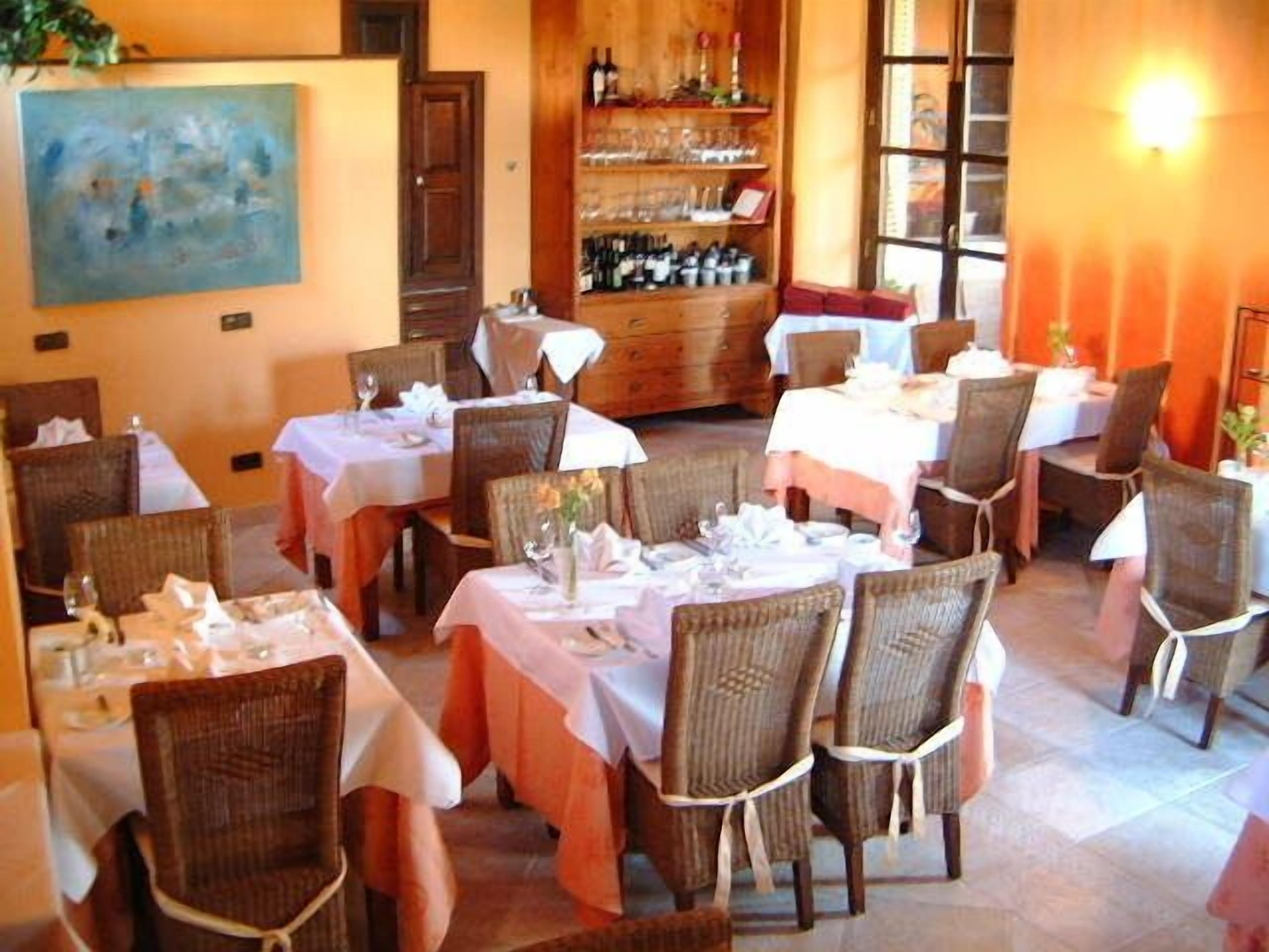 Un ristorante con diversi tavoli e sedie, una cantina e un quadro appeso al muro.