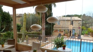 Une terrasse avec une piscine, des sièges d’extérieur et des plantes en pot.