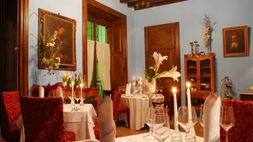 Comedor con mesas dispuestas para una comida, sillas y una araña.