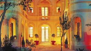 Un imposant bâtiment à plusieurs étages, doté d’une façade symétrique, de fenêtres en arc de cercle et d’une cour intérieure.