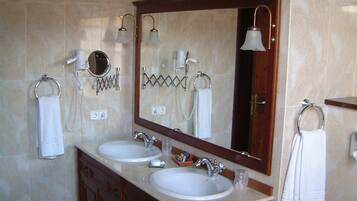 Un baño con dos lavamanos, un espejo grande y anillas para toallas.