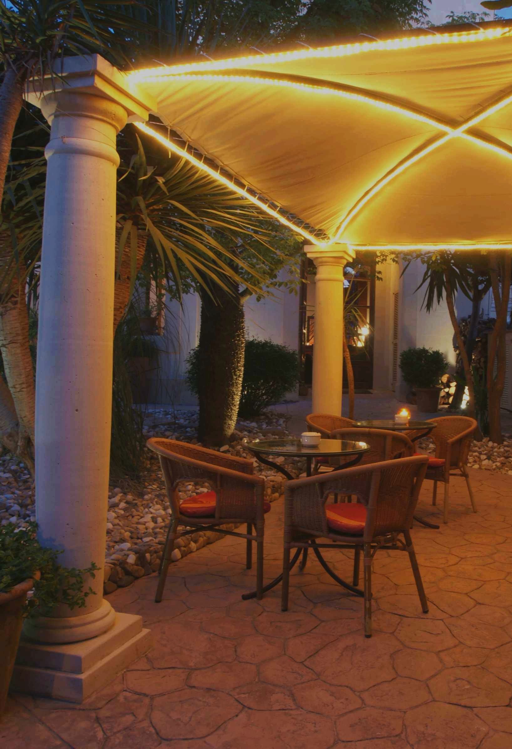 An outdoor patio area with a canopy, seating, and a table with a candle.