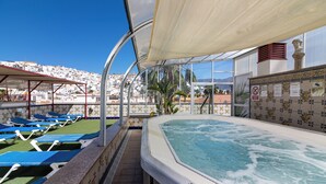 A rooftop pool area with blue lounge chairs, a hot tub, and a view of a cityscape. - Hotel Avenida Tropical (Salobreña)