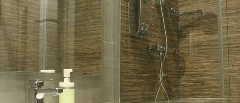 A modern bathroom with a glass-enclosed shower, a white sink, and a marble countertop.