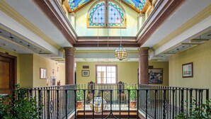 A spacious interior with a high ceiling, a balcony with a wrought iron railing, and a large stained glass window. - Hotel Avenida Tropical (Salobreña)
