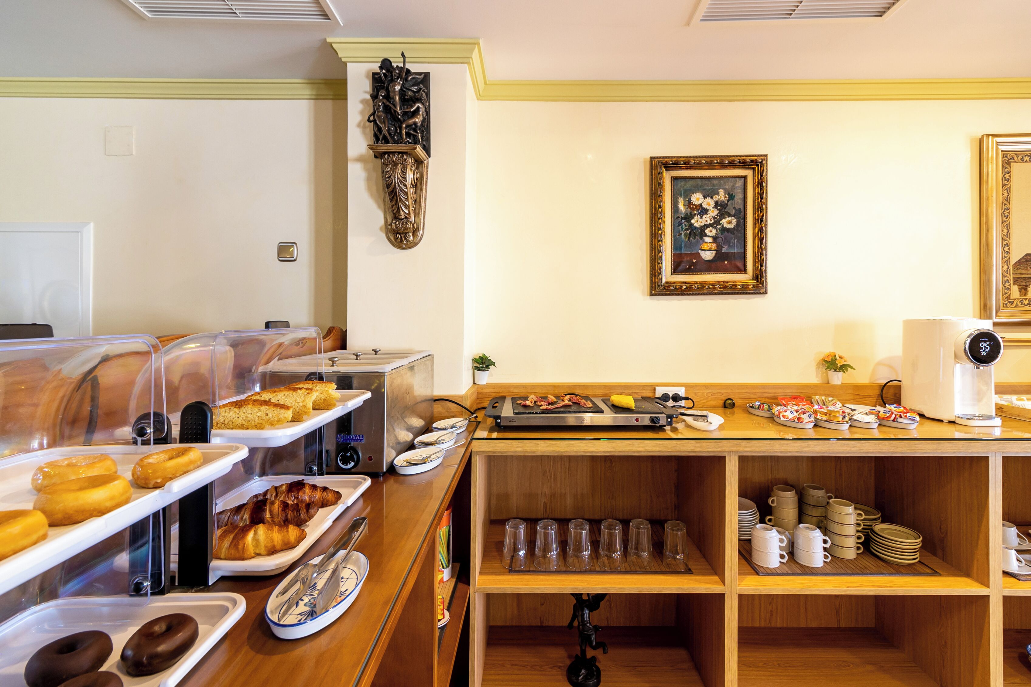 Un buffet de petit-déjeuner proposant divers pâtisseries, une machine à café et un élément décoratif mural.