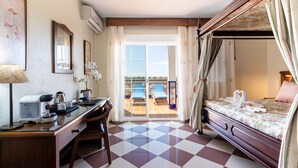 A hotel room with a checkered floor, a desk with a lamp, a bed with a canopy, and a view of a pool through the door. - Hotel Avenida Tropical (Salobreña)