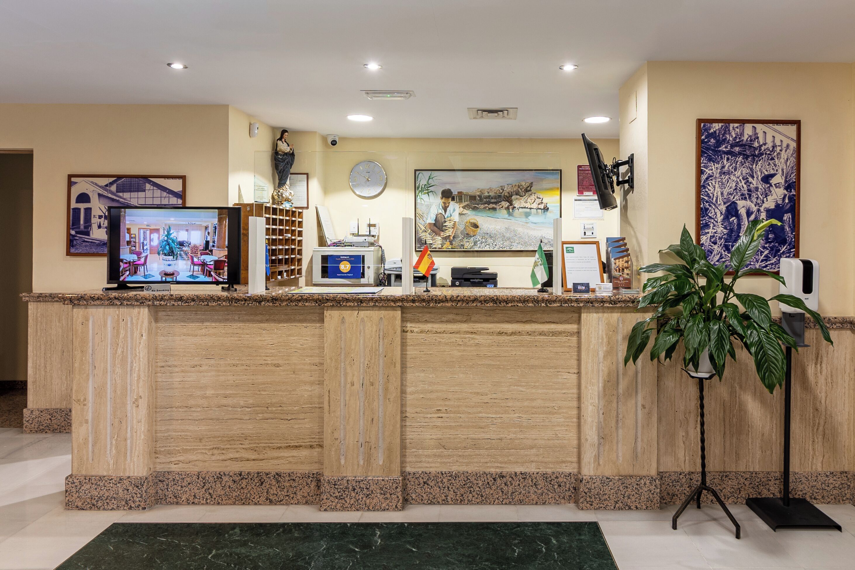 A reception desk with a television, a clock, and framed artwork on the wall.