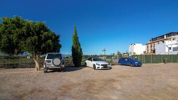 A parking lot with three cars, a tree, and a building in the background.