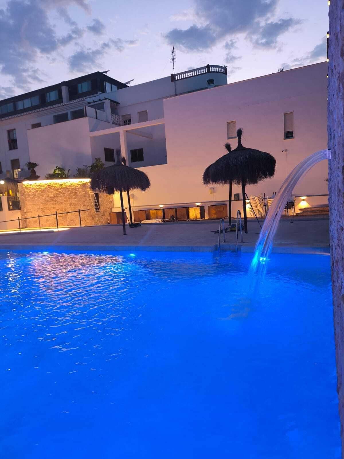 Una piscina con fuente, rodeada de edificios de diseño moderno.