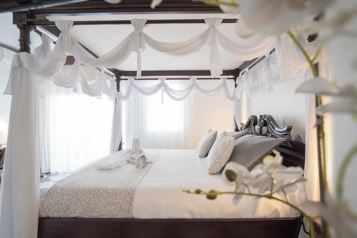 A bedroom with a canopy bed, a large window, and a view of the outdoors.