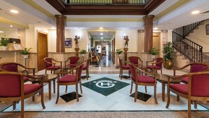 A hotel lobby with a central seating area, a staircase, and a reception desk. - Hotel Avenida Tropical (Salobreña)