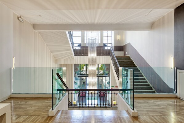 A spacious interior with a grand staircase, a chandelier, and a view of the outdoor area.