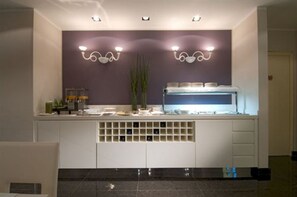 A modern bathroom with a vanity, two wall-mounted lights, a mirror, and a shelf with toiletries.