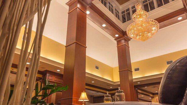 A luxurious lobby with high ceilings, ornate wooden columns, a chandelier, and leather seating. - Hilton Garden Inn Bangor (Bangor)