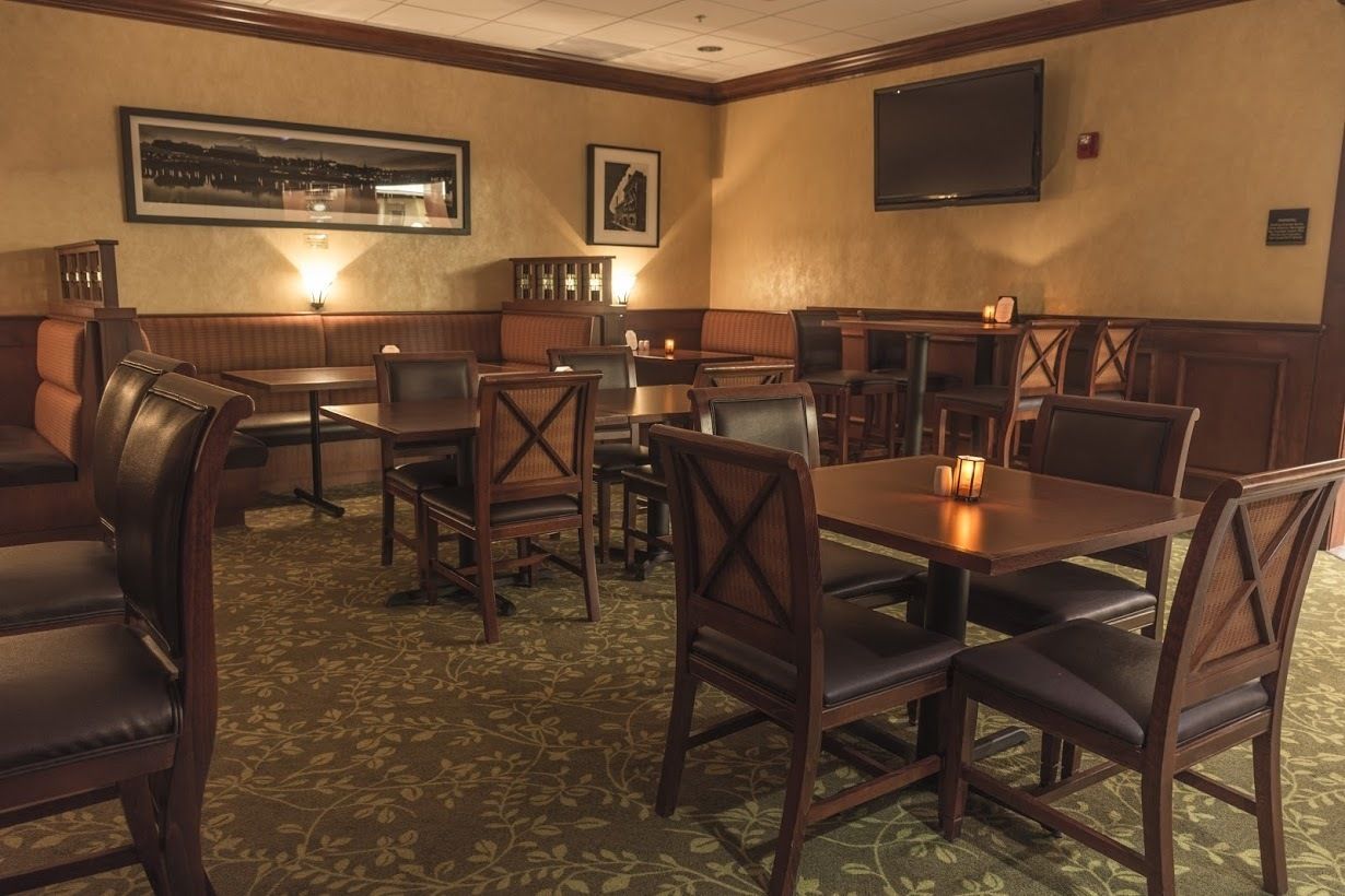 A restaurant with booths and tables, a patterned carpet, and framed pictures on the walls.