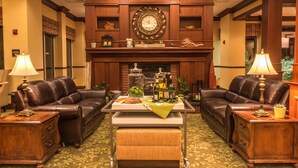 A hotel lobby with two leather sofas, a central coffee table, a fireplace, and a large wall clock. - Hilton Garden Inn Bangor (Bangor)