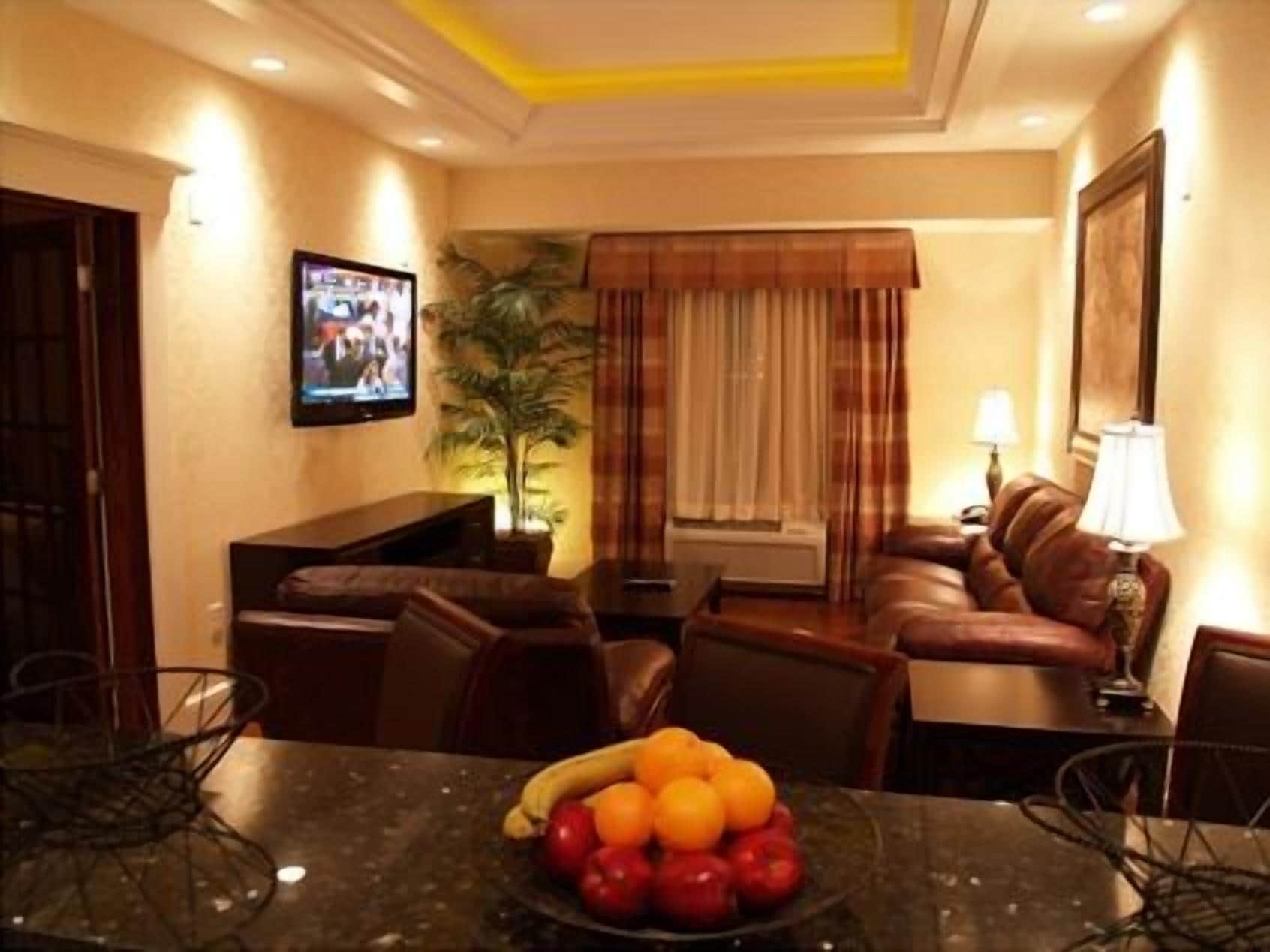 Une chambre d’hôtel équipée d’une table à manger, d’un canapé, d’une télévision et d’un panier de fruits.