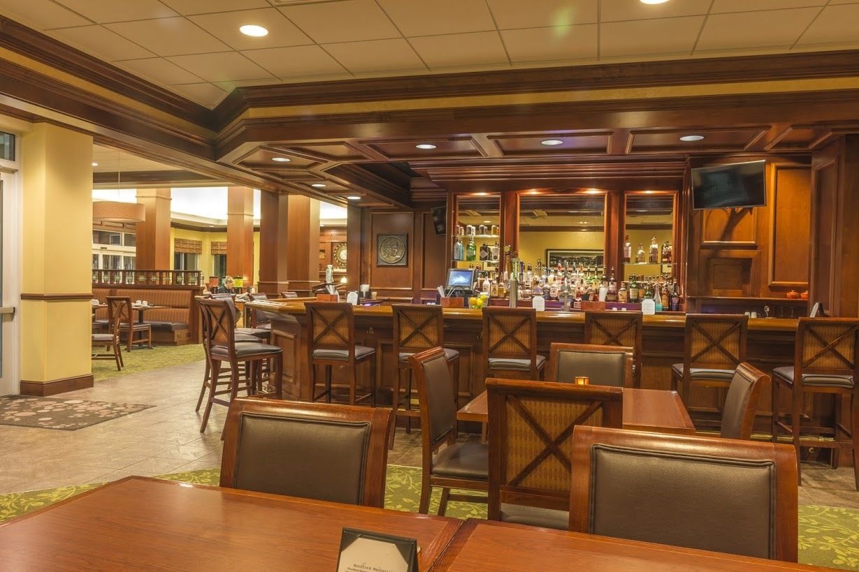 A hotel lobby with a bar area, seating arrangements, and a clock on the wall.