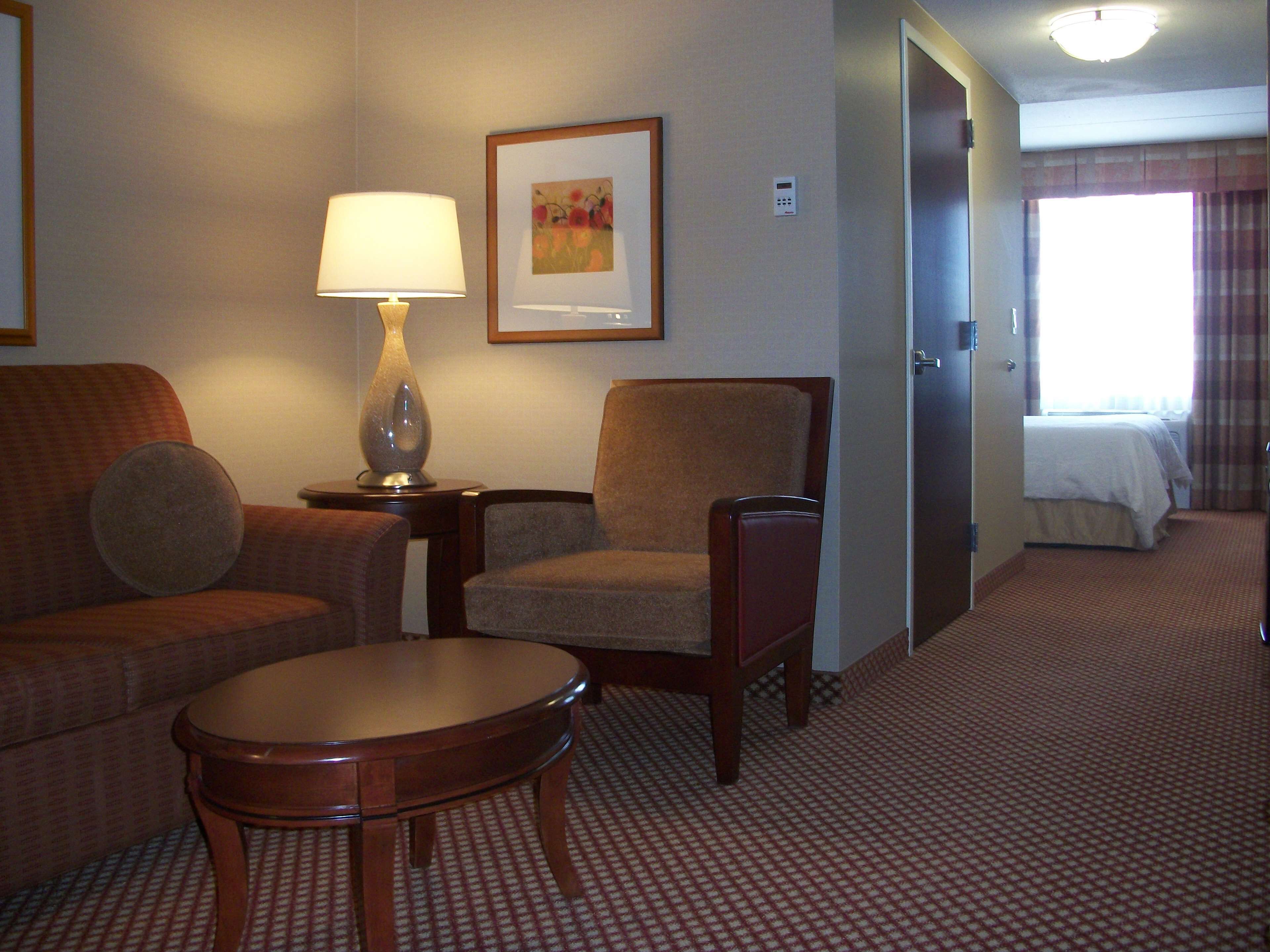 A hotel room with a sofa, armchair, small table, and a bed.
