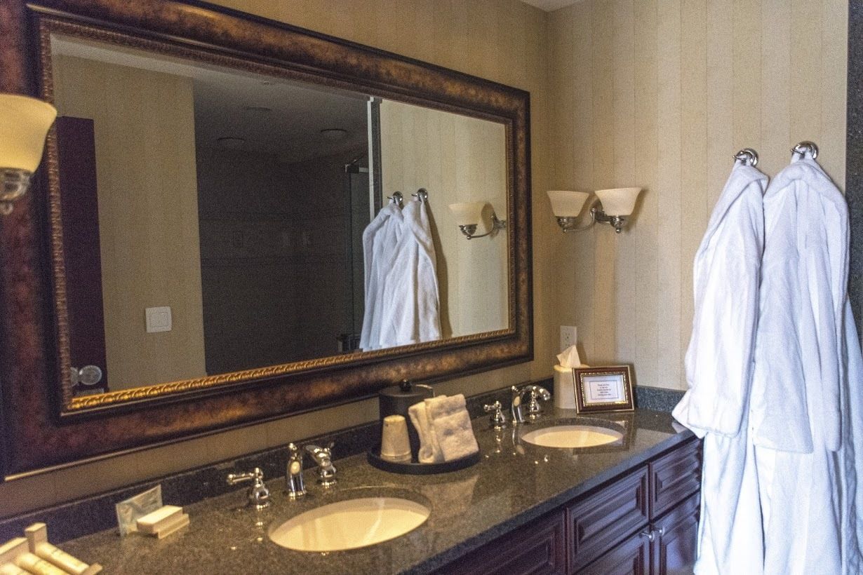 A bathroom with a large mirror, two sinks, and a towel rack with towels.