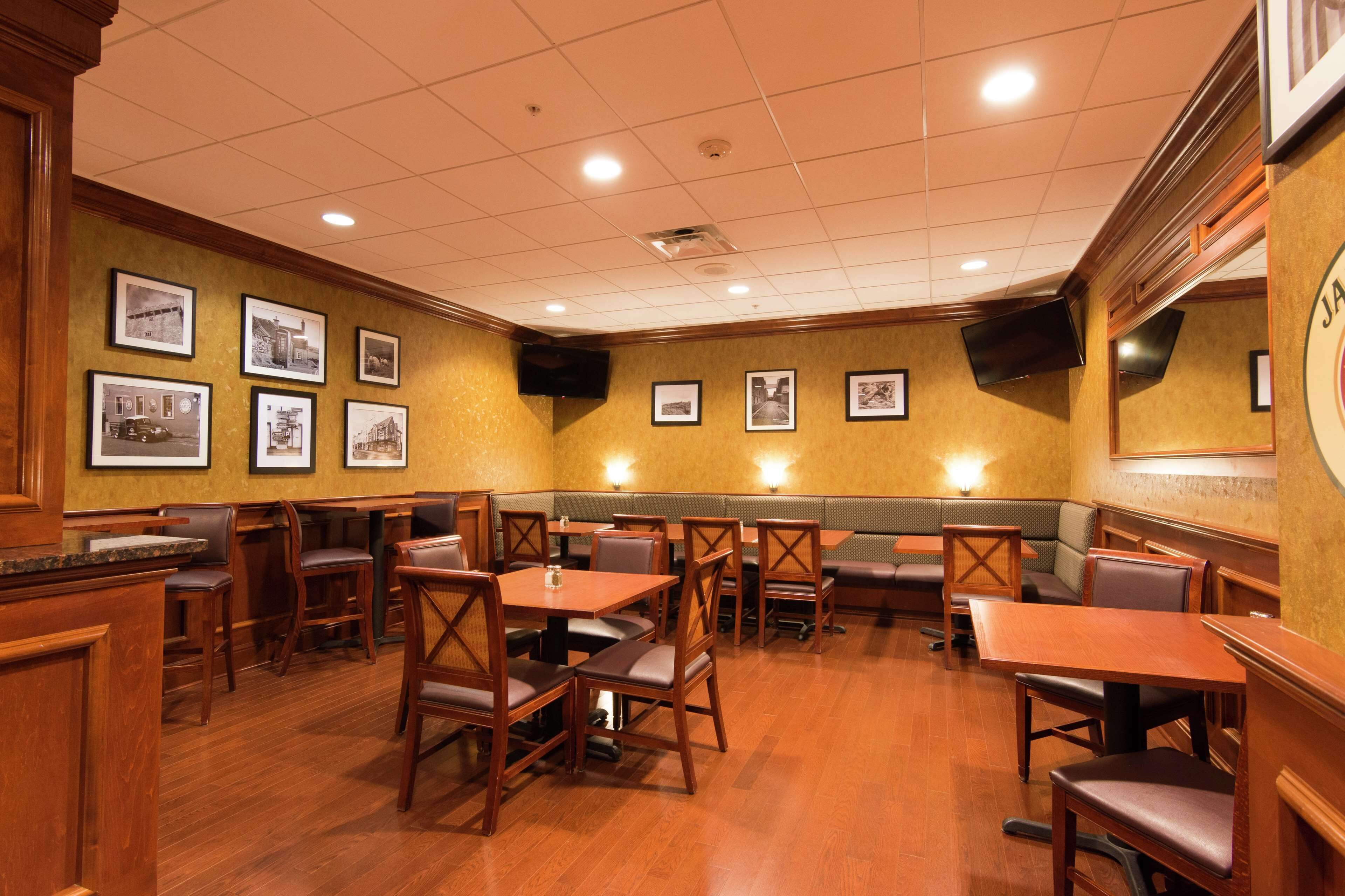 A restaurant with wooden tables and booths, framed pictures on the walls, and a tiled ceiling.