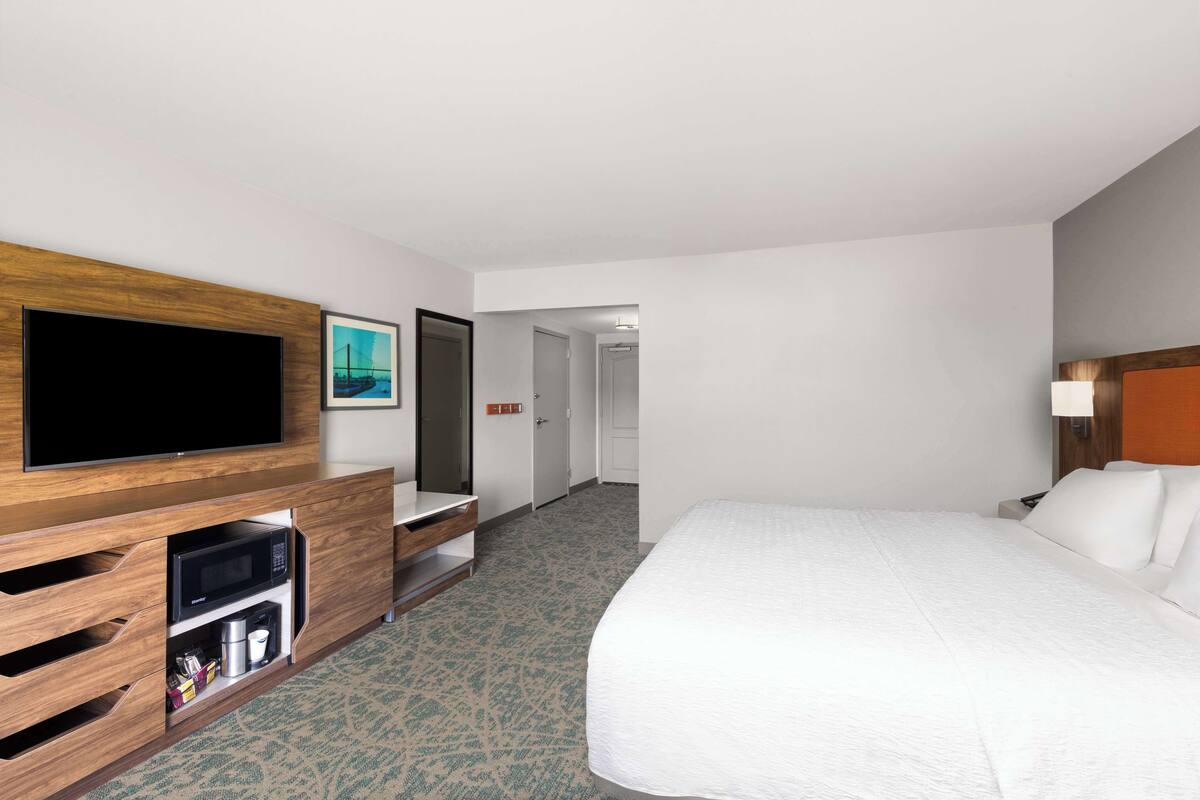 A hotel room with a large bed, a flat-screen TV, a microwave, and a coffee maker.