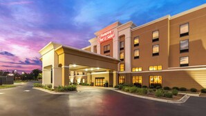 A Hampton Inn & Suites hotel with a modern facade, a covered entrance, and a landscaped front yard.
