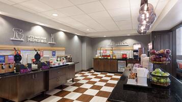 A bakery counter with waffle makers, a coffee station, and a fruit display.