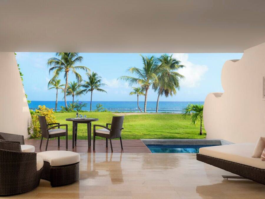 Une chambre avec vue sur l’océan, une piscine et du mobilier d’extérieur.