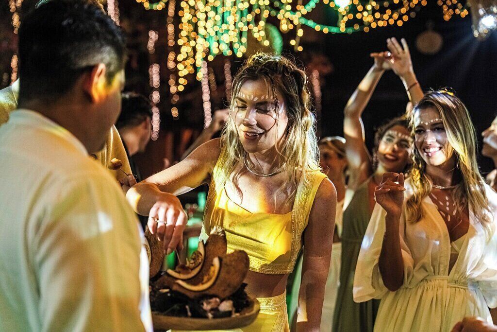 A group of people at a social event, possibly a party or celebration, with string lights in the background.