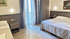 Une chambre d’hôtel comprenant un lit, une table de chevet, une armoire et une fenêtre avec des rideaux.