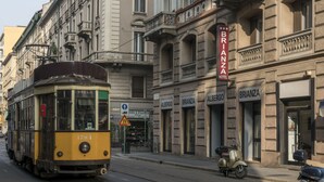 Un tramway jaune dans une rue de la ville, avec un bâtiment portant l’inscription « BRIANZA HOTEL » et « ALBERGO » en arrière-plan.