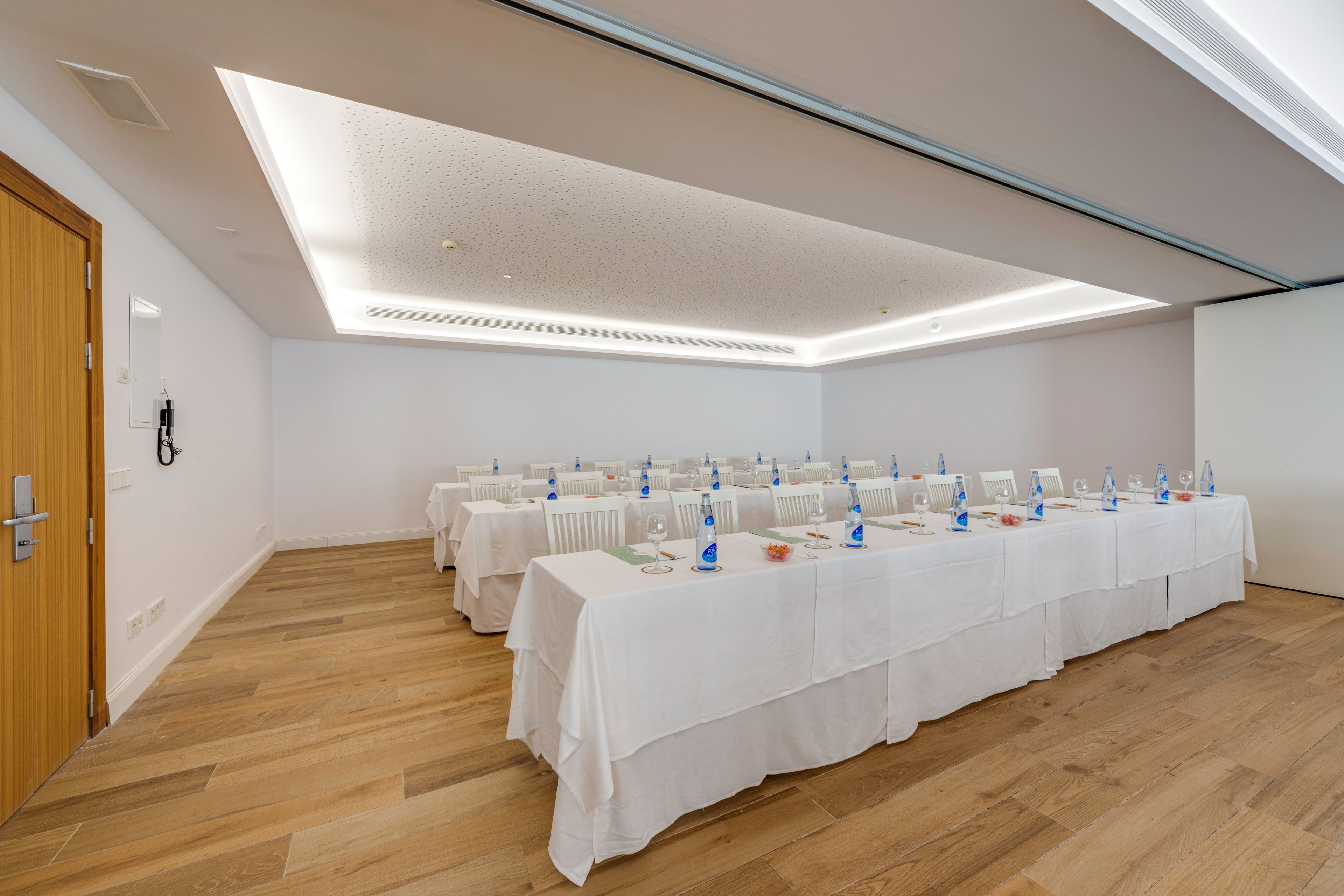 A conference room with a long table set for a meeting, equipped with water bottles and glasses.
