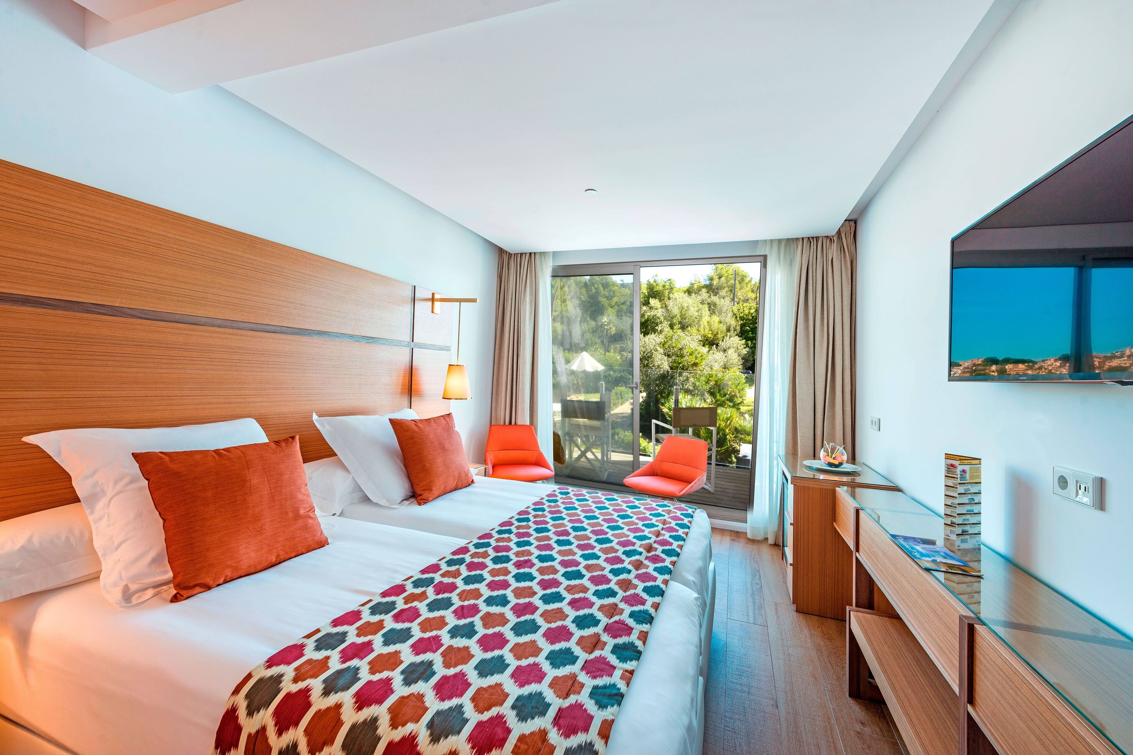 A hotel room with a large bed, a desk, and a view of the outdoors.