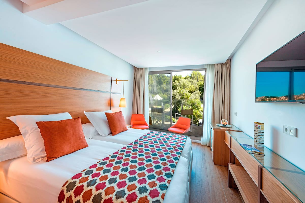 A hotel room with a large bed, a desk, and a view of the outdoors.