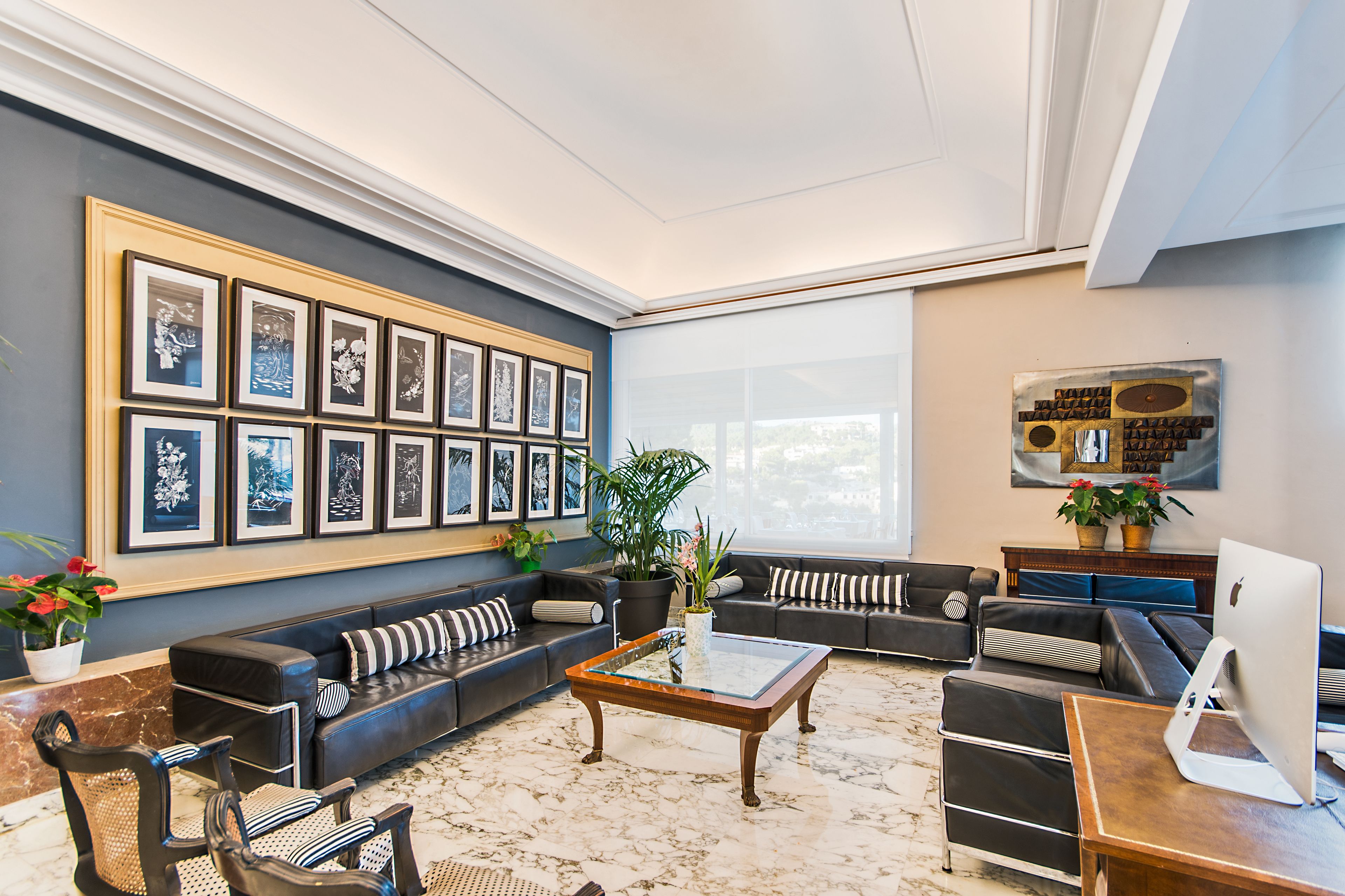 A modern living room with a sectional sofa, a glass coffee table, and a large framed picture collection on the wall.