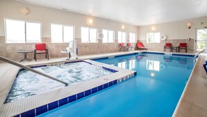 Una piscina con hidromasaje, sillas rojas y una mesa.