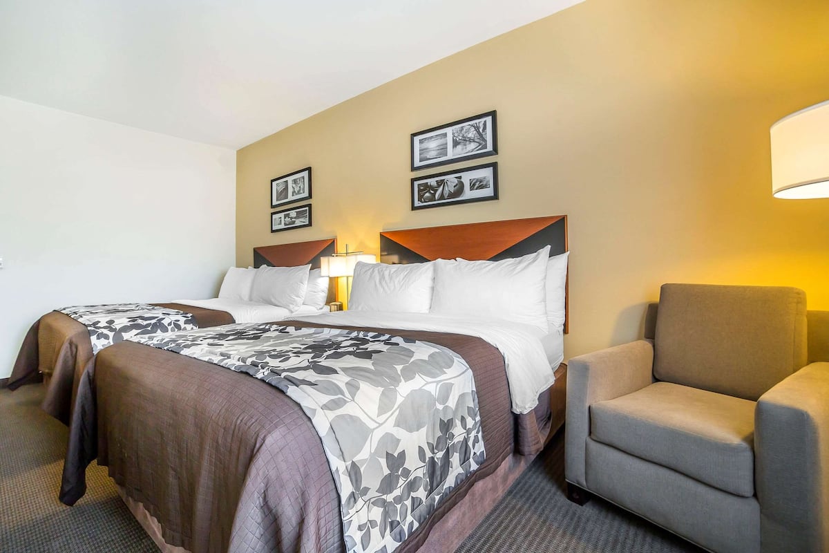 A hotel room with two beds, a sofa, and framed pictures on the wall.