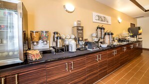 Montaje de bufé con diferentes estaciones de comida y bebida, que incluyen un refrigerador, máquinas de café y dispensadores de condimentos.