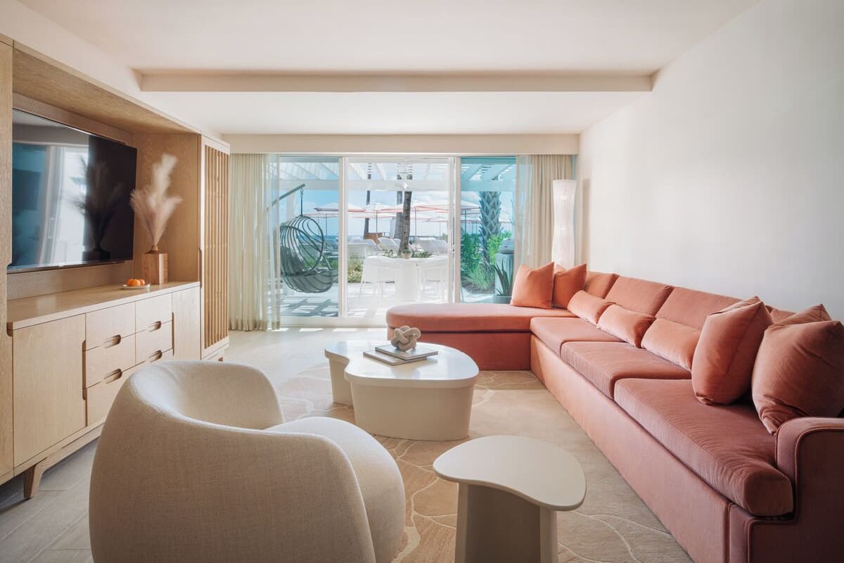 A modern living room with a sofa, two armchairs, a coffee table, and a TV on a wooden cabinet.