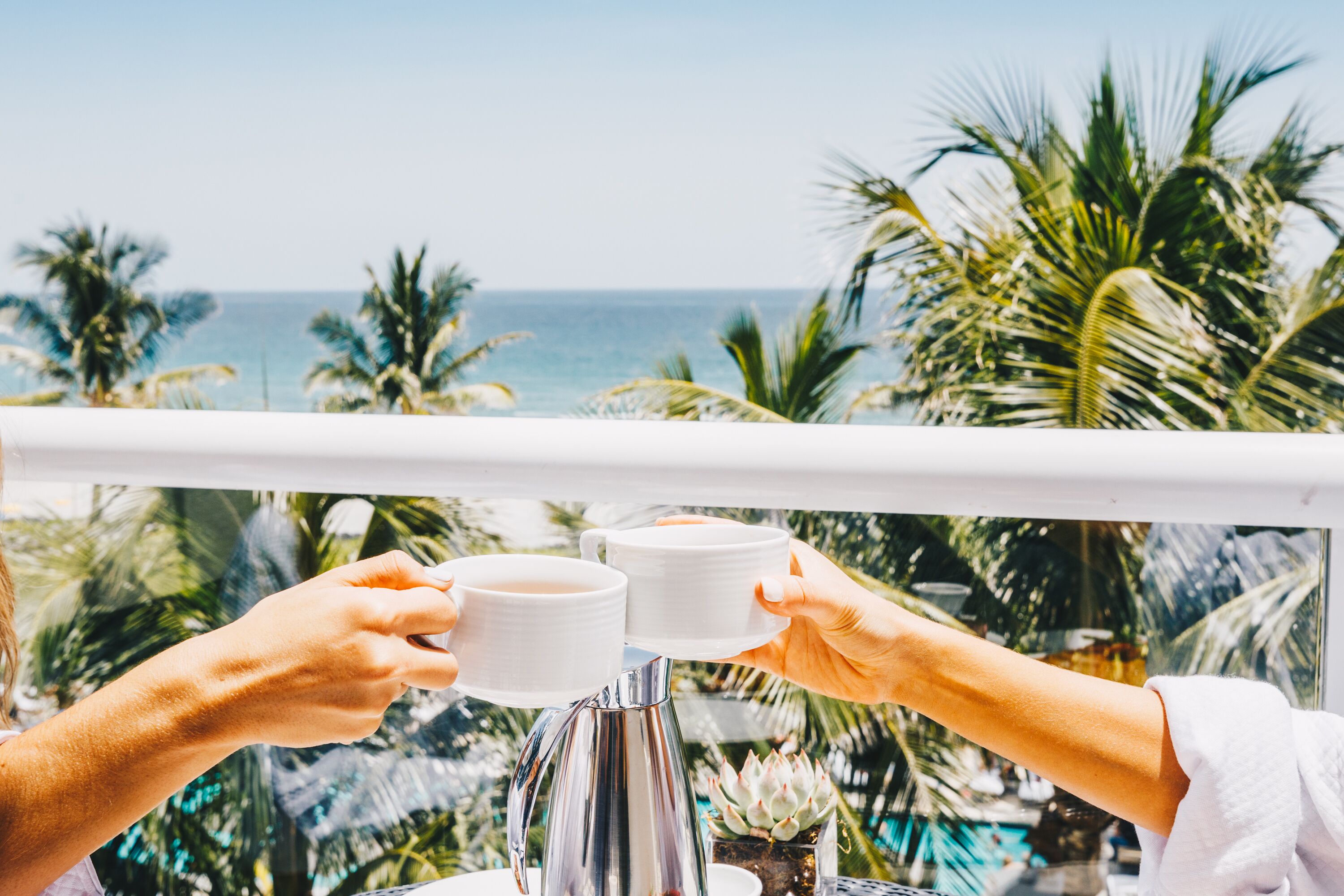 A balcony with a view of the ocean and palm trees.