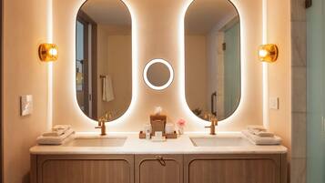 A modern bathroom with two sinks, a large mirror, and built-in towel racks.